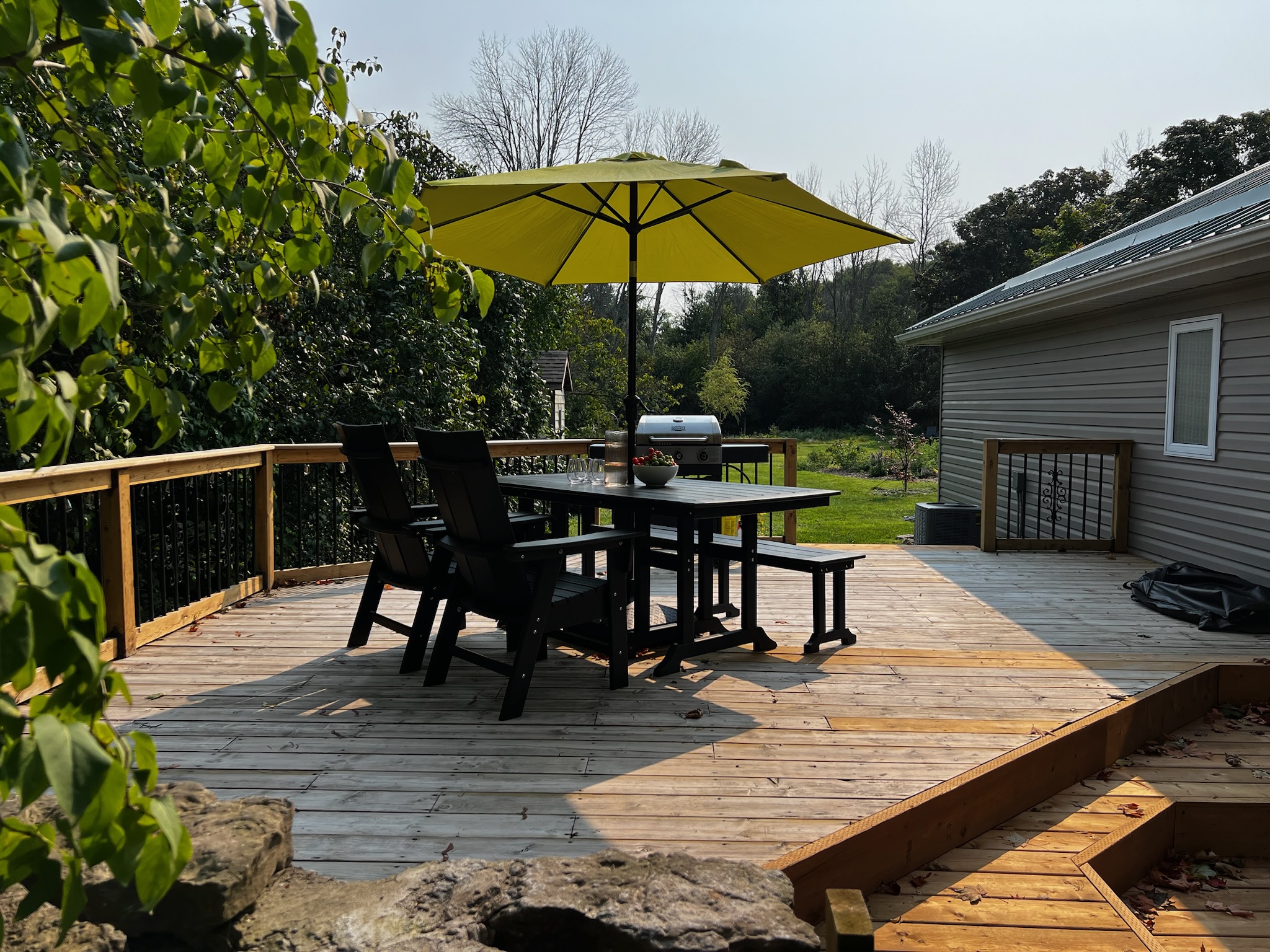 Photo of SquirrelHaus PEC's outdoor deck with apple green umbrella above a black dining table.