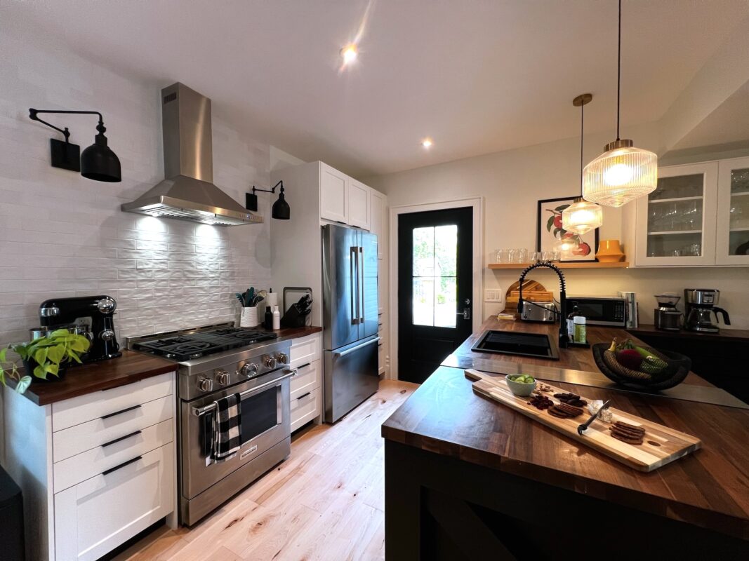 SquirrelHaus PEC kitchen with commercial-styled appliances, ample prep space, natural light, and a glass door to the deck.