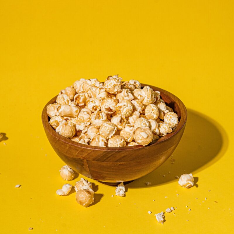 Photo: A wooden bowl overflowing with caramel corn against a yellow background
